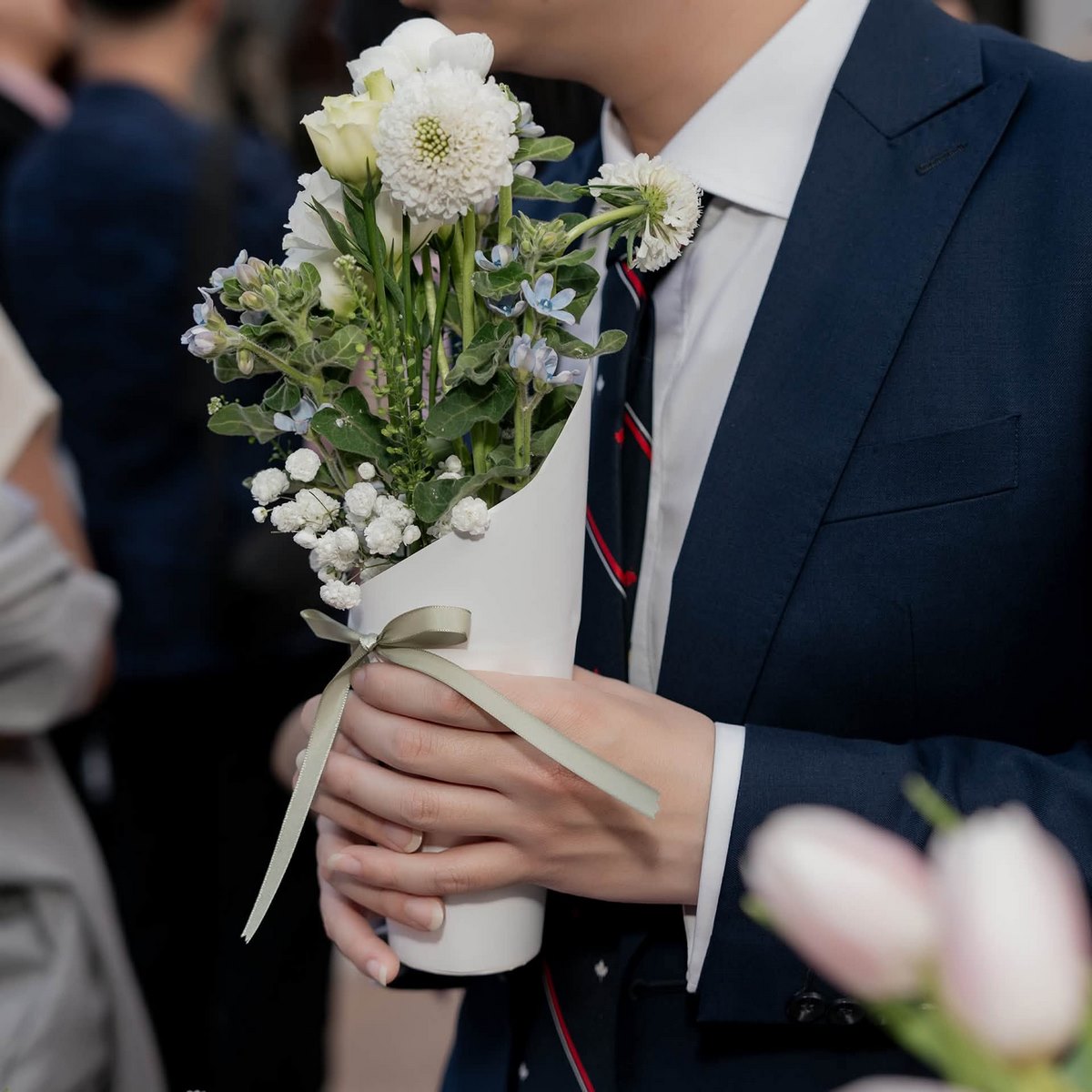 Một vị khách cầm bó hoa tại đám cưới Ngọc Linh và Long Sơn